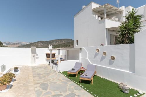 a white house with two chairs on a patio at Ocean Blue Villa in Agiassos