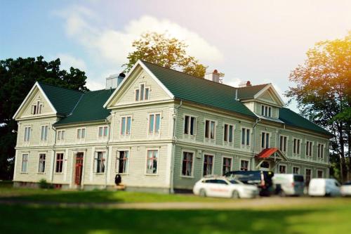 uma grande casa branca com carros estacionados em frente em Piece of Hjo Vandrarhem em Hjo