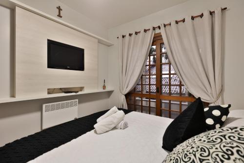a bedroom with a bed with a tv on the wall at Apartamento de 1 quarto in Gramado