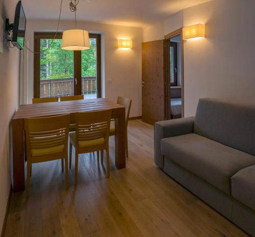 un soggiorno con tavolo da pranzo e divano di Appartamento con terrazza di mq 40 con vista Pale di San Martino a San Martino di Castrozza