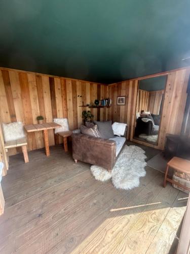 a living room with a couch and a table at Secluded Lakeside Off Grid Cabin with Outdoor Bath in Rhosneigr
