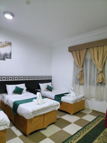 - une chambre avec 2 lits et un sol en damier dans l'établissement فندق مناسك الرشاد الفندقية, à La Mecque