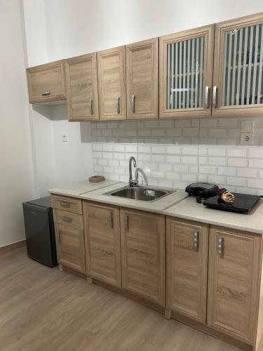a kitchen with wooden cabinets and a sink at Paola’s apartments near Athens Airport in Spáta