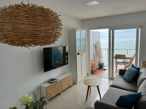 ein Wohnzimmer mit einem Sofa und einem Flachbild-TV in der Unterkunft Apartamento Primera línea playa in Las Palmas de Gran Canaria
