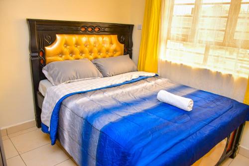 ein Bett mit einer blauen Decke und einem Fenster in der Unterkunft Karibu Place Kamakis- Opp Greenspot Gardens in Ruiru