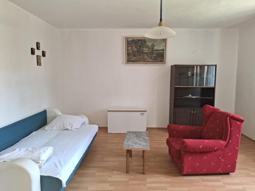 ein Wohnzimmer mit einem Sofa und einem roten Stuhl in der Unterkunft Kuća za odmor - MAJA in Kruševac