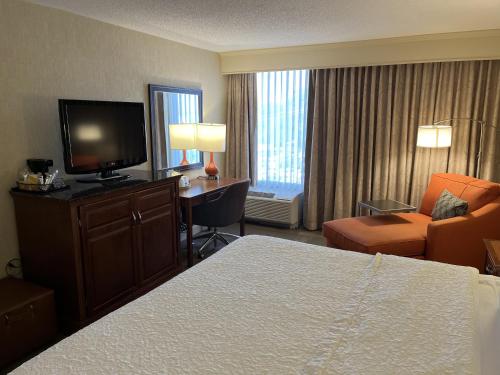 a hotel room with a bed and a desk and a television at Wingate by Wyndham St Louis Airport in Saint Ann