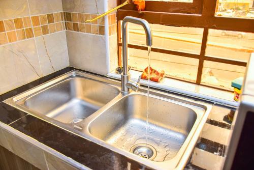 a kitchen sink with water running from a faucet at Karibu Place Kamakis- Opp Greenspot Gardens in Ruiru