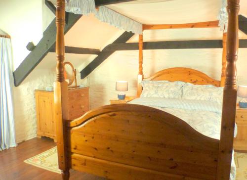 1 dormitorio con cama de madera con marco de madera en Old Newham Farm, en Camelford