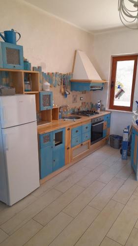 La cuisine est équipée de placards bleus et d'un réfrigérateur blanc. dans l'établissement Residence 3, à Montauro