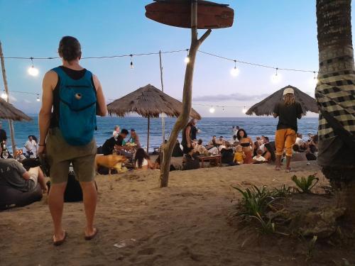 Ein Mann spaziert mit einer Menschenmenge am Strand entlang. in der Unterkunft Seseh Hacienda in Munggu