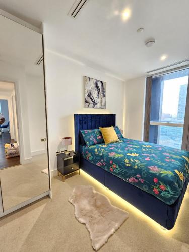 1 dormitorio con cama azul y espejo en 2 bed Luxurious apartments Canary Wharf en Londres