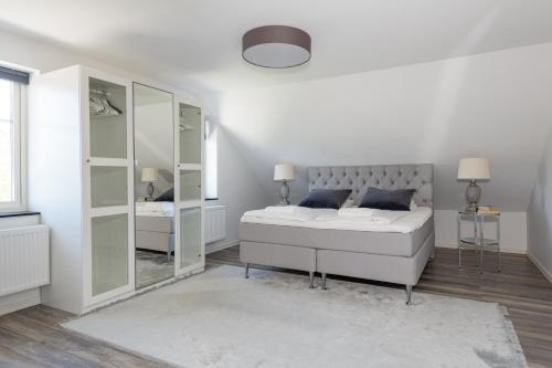 a white bedroom with a bed and a mirror at The Rose Valley in Gothenburg