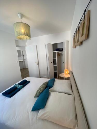 um quarto com uma grande cama branca com almofadas azuis em COSY CONFORT LA PEROUSE 1A coeur de ville et plage em Concarneau