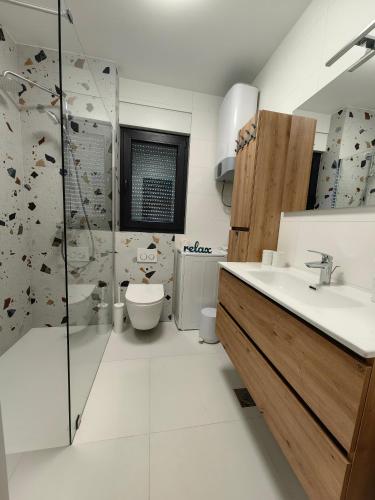 a bathroom with a sink and a shower and a toilet at Apartments SORELLE in Podstrana