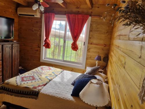 een slaapkamer met een bed in een blokhut bij Cabaña La Querida in Santa Rosa