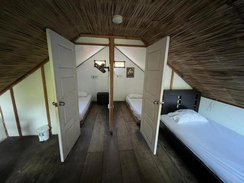 Habitación pequeña con 2 camas y techo de madera. en Hostal Kaia, en Santa Marta