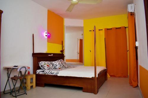 um quarto com uma cama com paredes laranja e amarela em Chez mimi em Cotonou