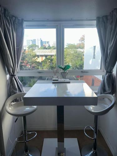 a table and two stools in front of a window at 1 Bedroom Flat, Bournemouth in Bournemouth