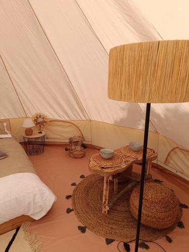 een kamer met een tent met een tafel en een bed bij Tente mongole " ô Rêves Atypiques" in Boucé