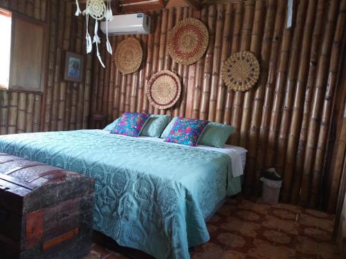 a bedroom with a bed with blue sheets and a wooden wall at Relax en Aguaclara, su Castillo de Arena soñado! in Ballenita
