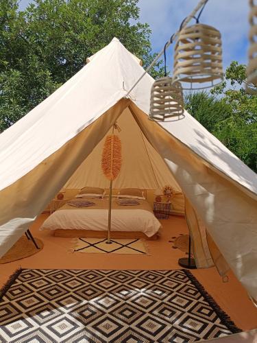een witte tent met een bed en twee stoelen bij Tente mongole " ô Rêves Atypiques" in Boucé