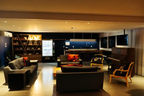 ein Wohnzimmer mit Sofas, einem Klavier und einer Küche in der Unterkunft Cris Hotel in Florianópolis