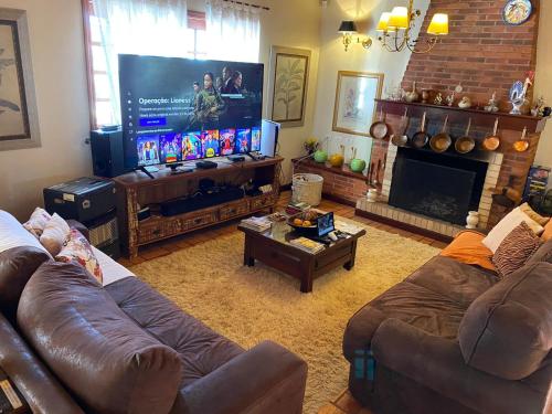 a living room with two couches and a large screen television at Pousada Chateau Colinas in Campos do Jordão