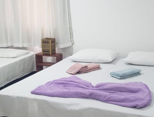 a white bed with a purple blanket on it at Casa do Mutá in Porto Seguro