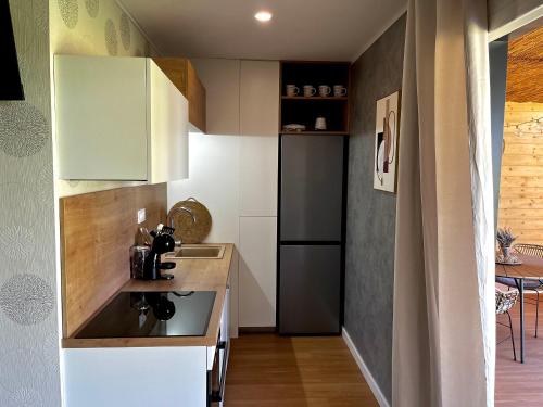 eine kleine Küche mit weißen Schränken und einem schwarzen Kühlschrank in der Unterkunft Premium mobile home Eden in Velenje