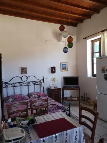 a bedroom with a bed and a table and a refrigerator at Με θέα το χωριό & το όρος Ζευς! in Apeiranthos
