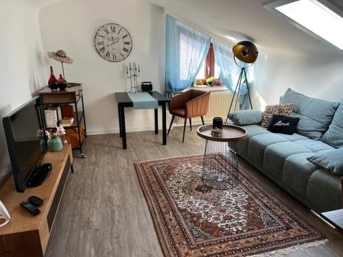 a living room with a couch and a table and a clock at Gemütliches Apartment für Messe, Job & Kurzurlaub im Grünen, Nähe Düsseldorf in Meerbusch