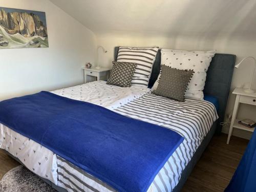 a bed with blue and white sheets and pillows at Gemütliches Apartment für Messe, Job & Kurzurlaub im Grünen, Nähe Düsseldorf in Meerbusch