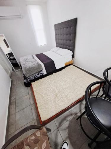 a small bedroom with a bed and a chair at Blanco Sereno - Depto 2 - 2 Min Malecón in Mazatlán