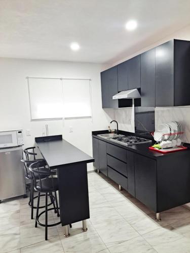 a kitchen with black cabinets and a black counter top at Blanco Sereno - Depto 2 - 2 Min Malecón in Mazatlán