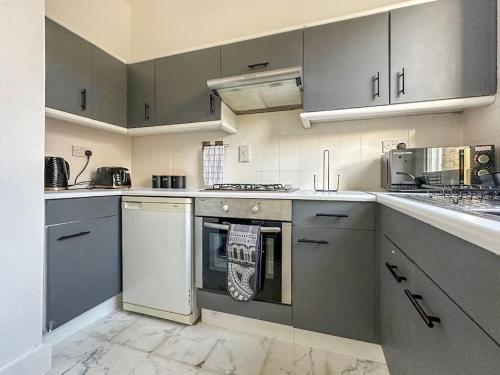 a kitchen with stainless steel appliances and gray cabinets at Luxe & Stylish 1 Bed Flat in London