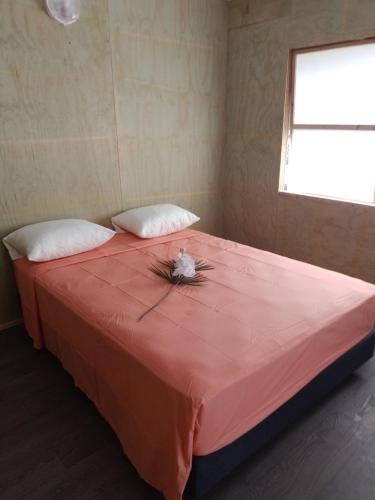 a bedroom with a pink bed with a bird on it at TEMAEVA LODGE in Nuku Hiva