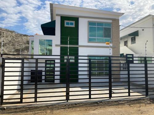 une maison avec une clôture devant elle dans l'établissement Hermoso hogar con bbq y piscina en Punta Blanca, à Punta Blanca