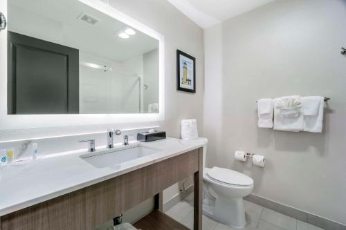 a bathroom with a sink and a toilet and a mirror at Comfort Inn & Suites Pacific - Auburn in Auburn