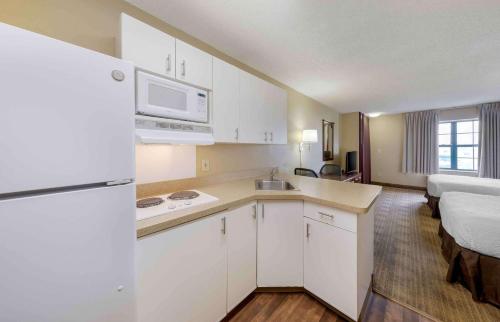 a kitchen with white cabinets and a room with a bed at Extended Stay America Suites - Orange County - Huntington Beach in Huntington Beach