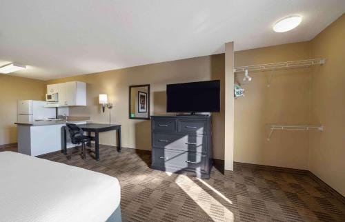 a hotel room with a bed and a desk and a television at Suburban Studios in Oklahoma City