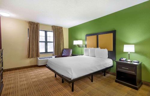 a hotel room with a bed and green walls at Suburban Studios Columbus Bradley Park in Columbus