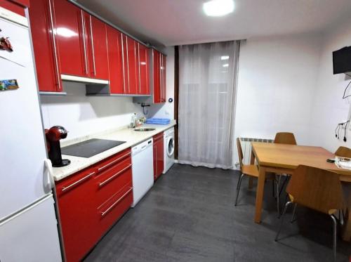 eine Küche mit roten Schränken und einem Holztisch in der Unterkunft Casa bella alma in Ramales de la Victoria