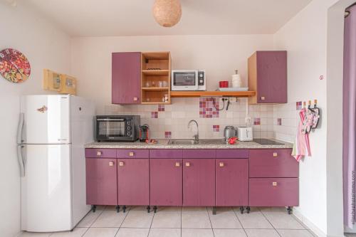 a kitchen with purple cabinets and a white refrigerator at T2 PITAYA, Trois-îlets vue mer in Les Trois-Îlets
