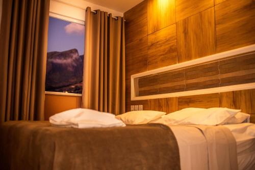 a hotel room with a bed with a window at Pousada Encanto das Montanhas in Caparaó Velho