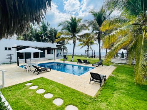 a backyard with a swimming pool and palm trees at Seaside Beach House, Monterrico in Santa Rosa