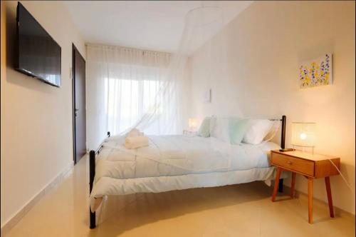 a white bedroom with a large bed and a television at Marathon Luxury Suites - Studio in Schinias