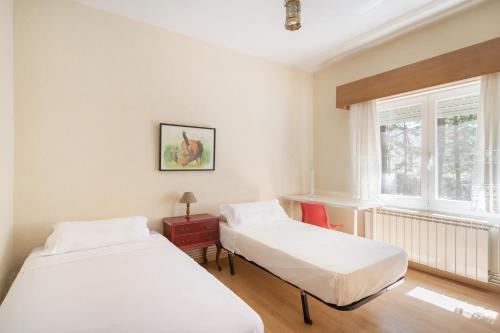 two beds in a room with a window at Casa Rural Los Olivos de Robledo de Chavela in La Estación