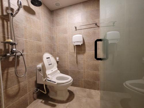 a bathroom with a toilet and a shower stall at Foxy Hotel in Busan