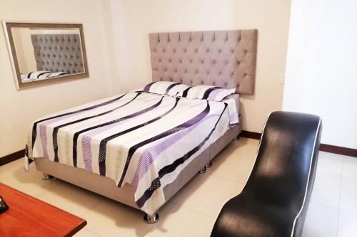 1 dormitorio con 1 cama grande y 1 silla negra en LOVENEST, en Lima